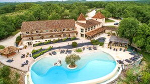 Een groot resort met een zwembad, terras en uitzicht op het omliggende bos.