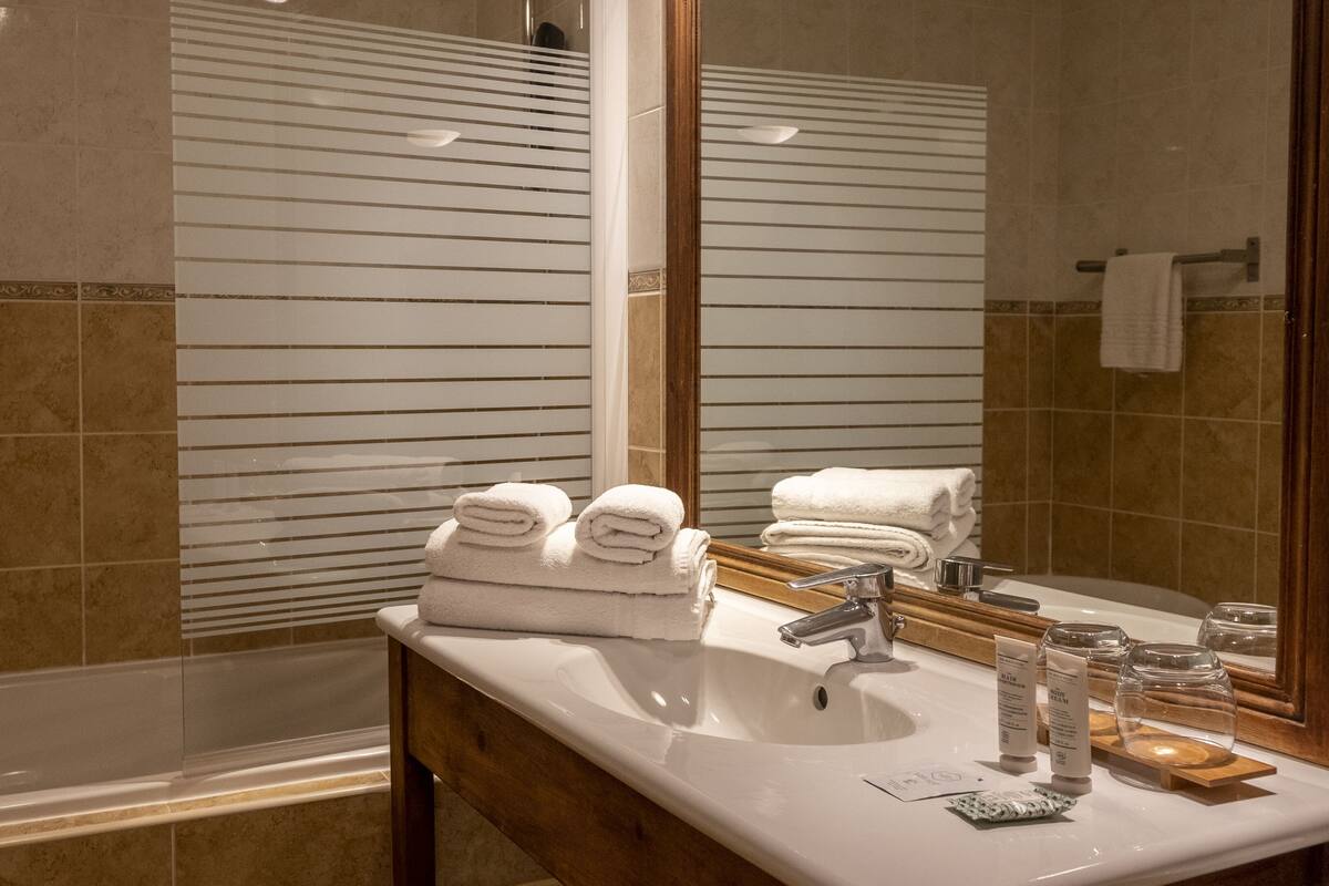 Een badkamer met een bad, een wastafel met toiletartikelen en een spiegel.