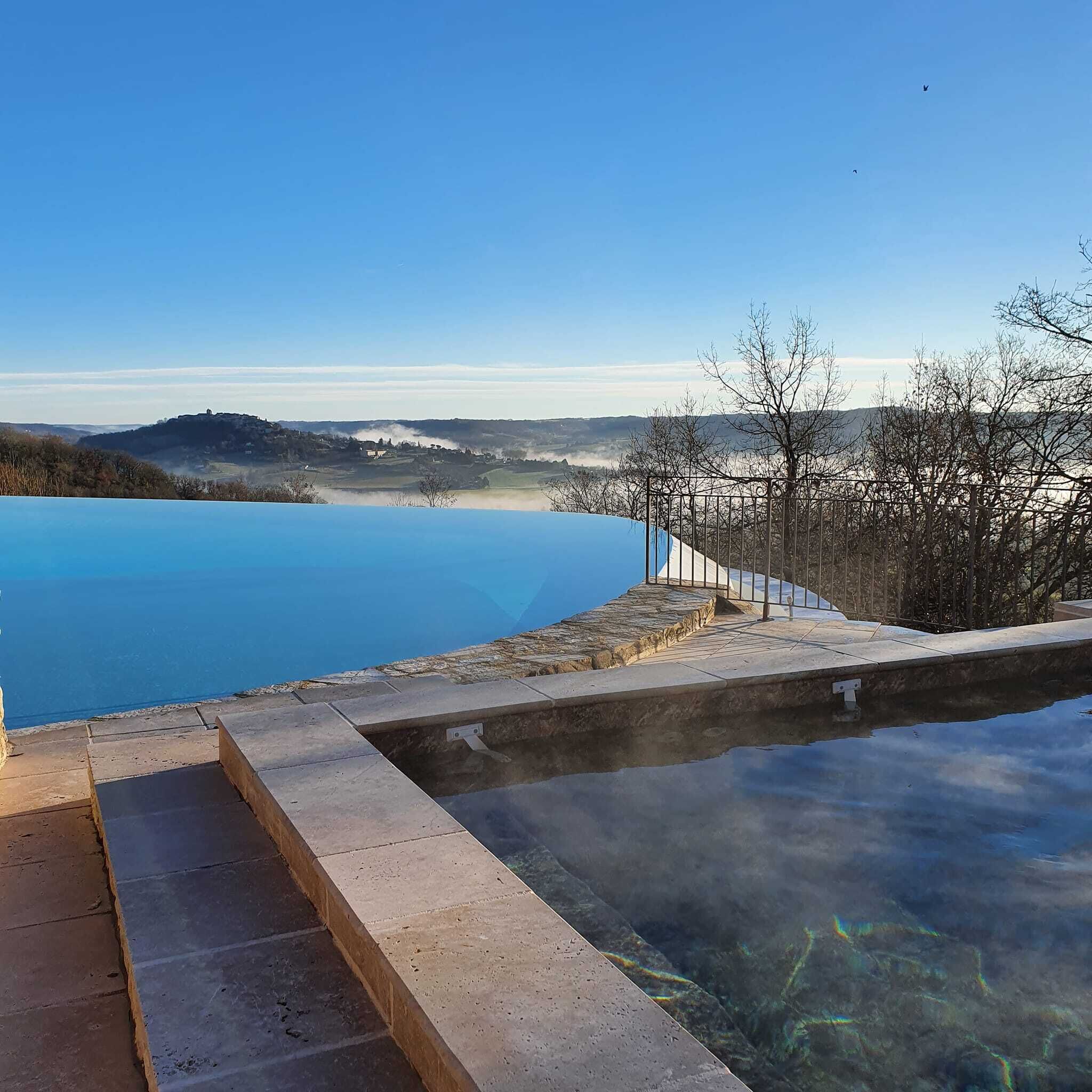 Vista clara de una piscina con escalones de acceso, rodeada de una valla metálica y árboles.