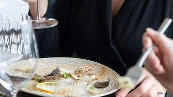 A person dining at a table with a wine glass, a plate with food, and a fork.
