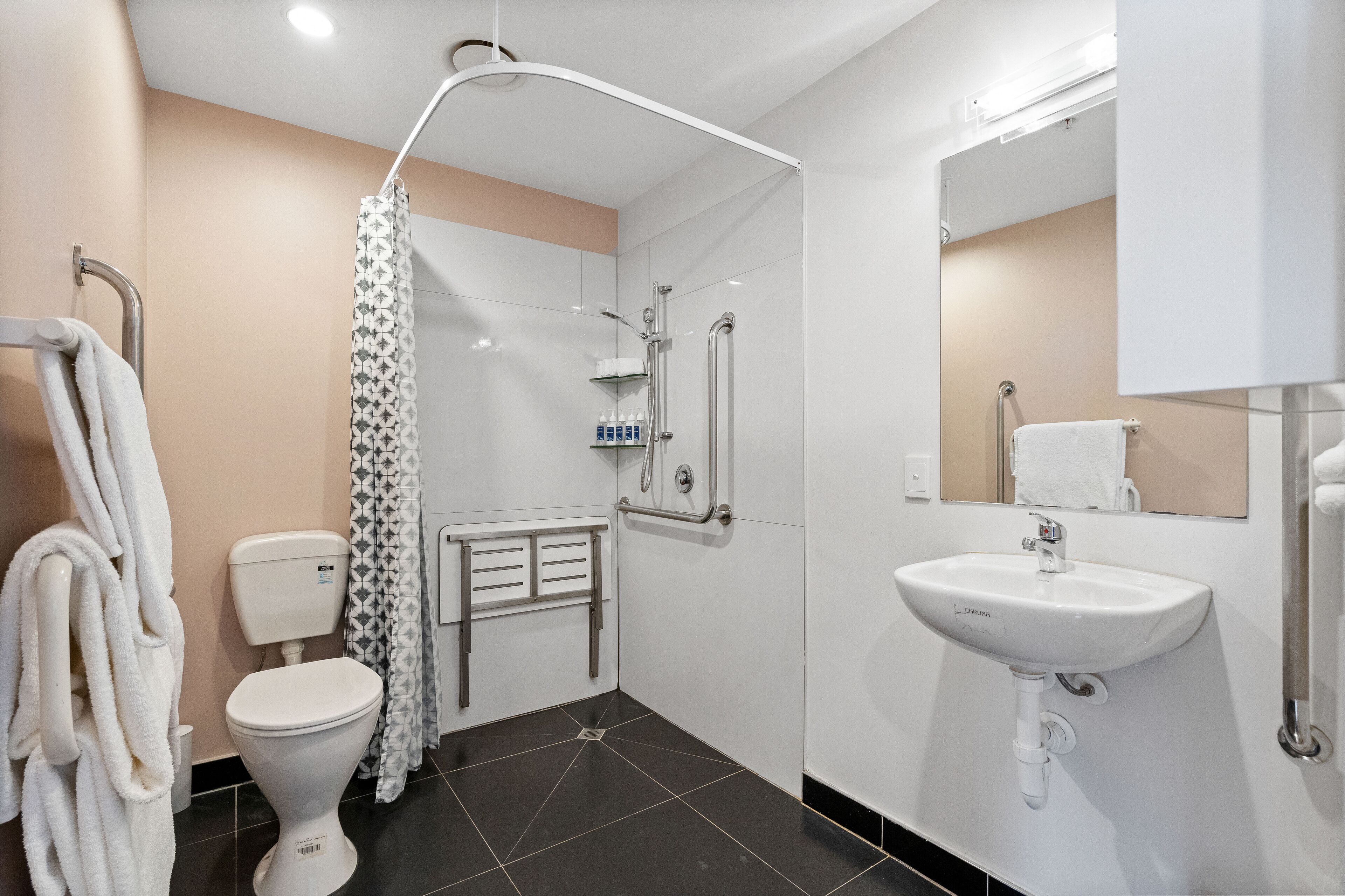 A modern bathroom with a toilet, shower, and sink.