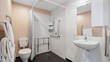 A modern bathroom with a toilet, shower, and sink.