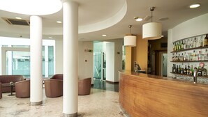 Un hall con mostrador de recepción, zona de estar y bar con botellas de licor.