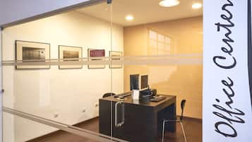 An office space with a reception desk, computer, and framed pictures on the wall.
