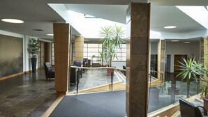 Un vestíbulo amplio con techo alto, suelo de piedra y mobiliario moderno.