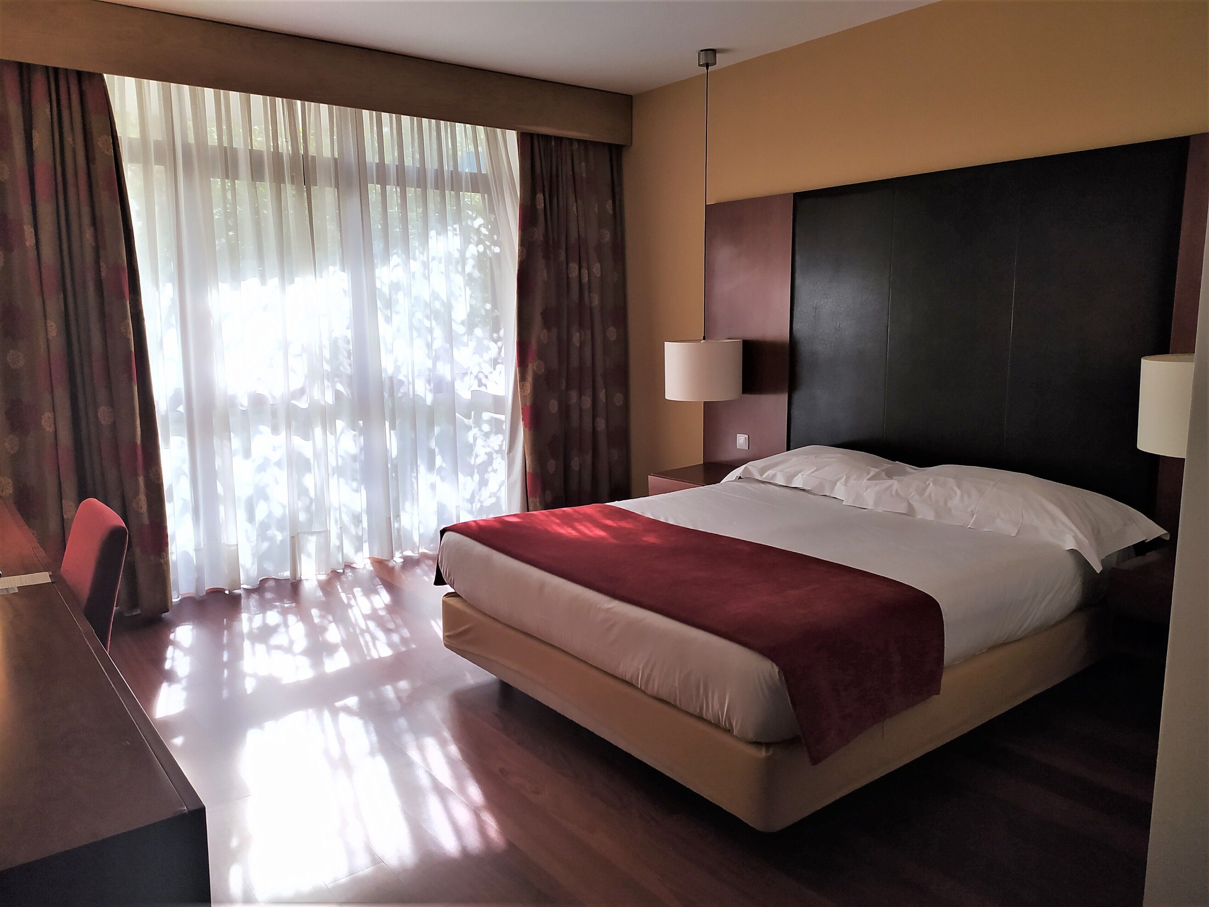 A hotel room with a bed, a desk, and a chair.