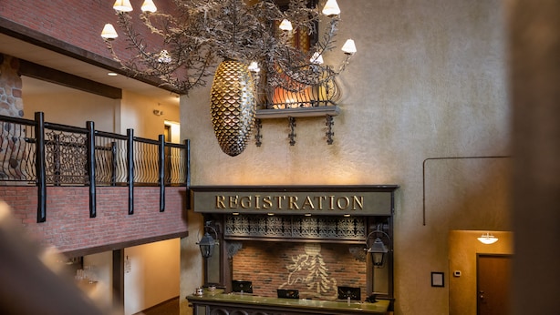 A registration desk with a brick wall backdrop, a chandelier, and a sign above it. - Stoney Creek Hotel Sioux City (Sioux City)