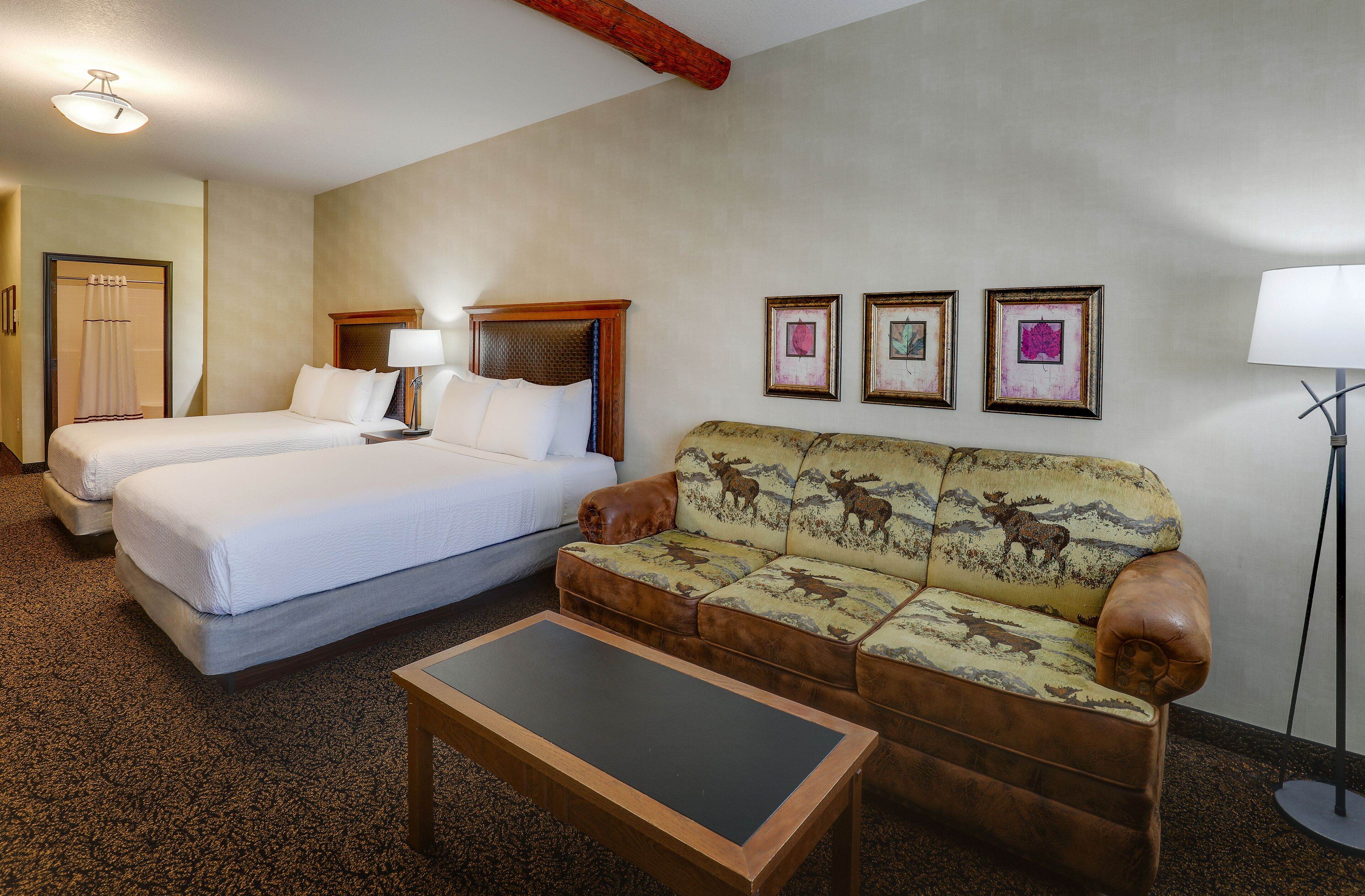 A hotel room with two beds, a sofa, a coffee table, and a lamp.