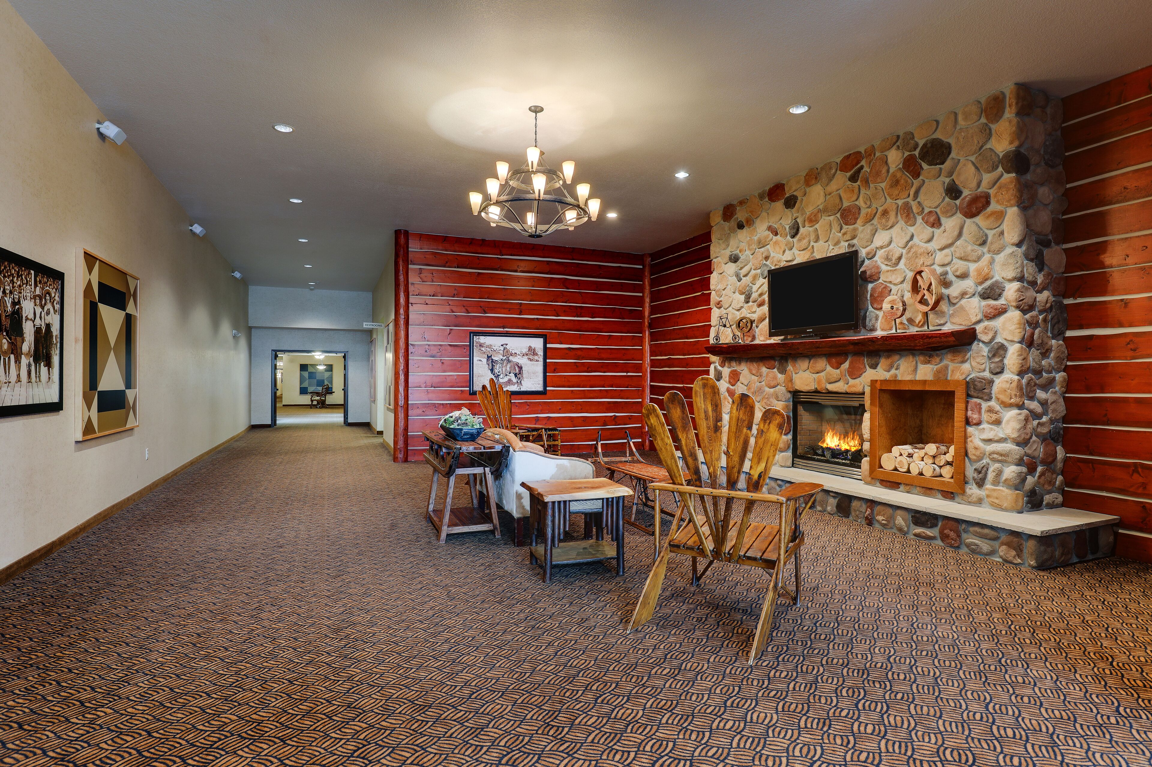 A spacious hallway with a fireplace, wooden walls, and patterned carpet.