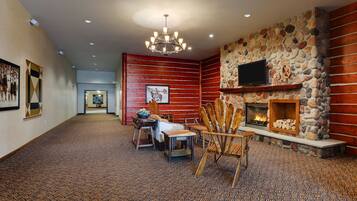 A spacious hallway with a fireplace, wooden walls, and patterned carpet.