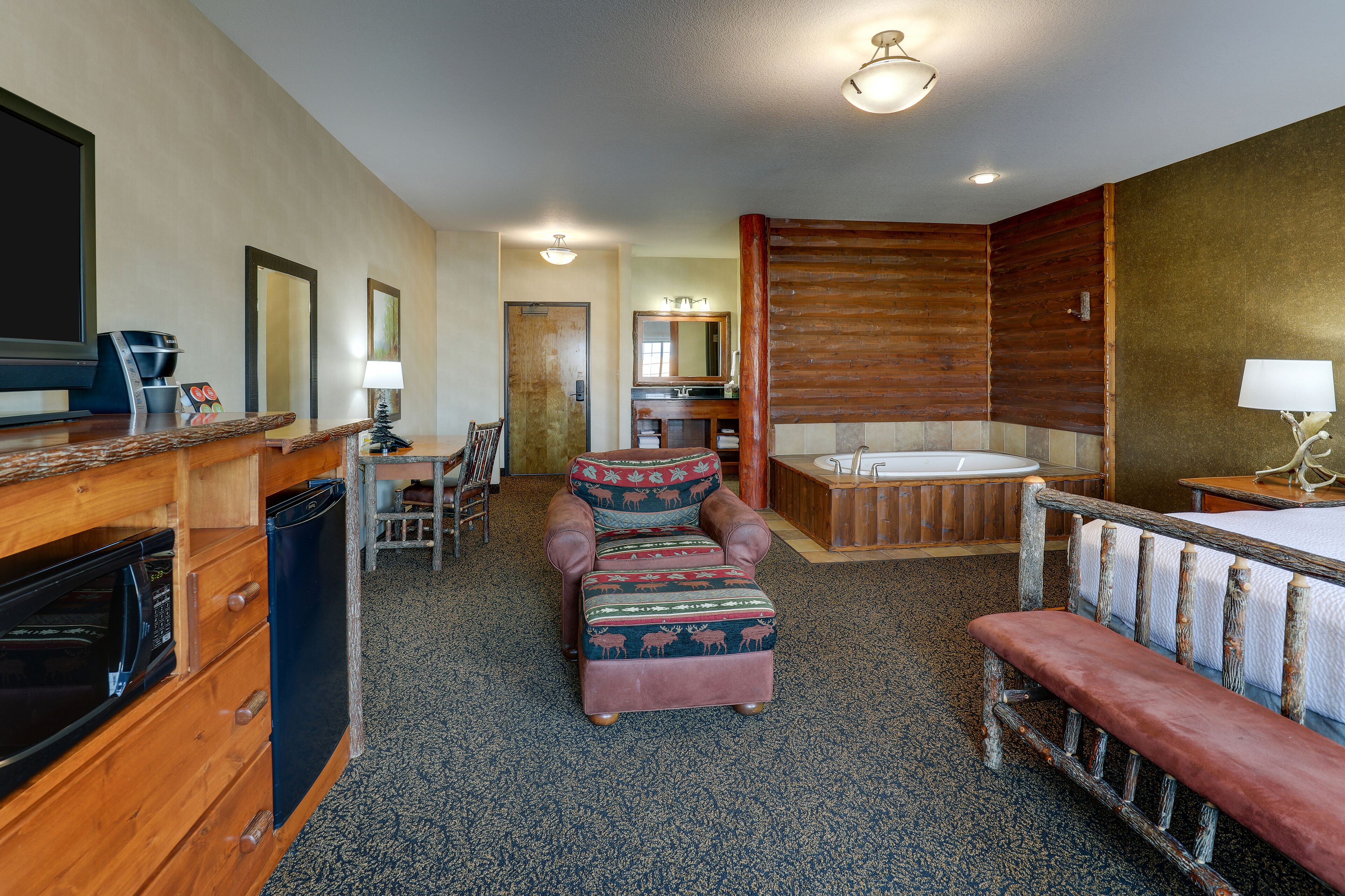 A cozy room with a wooden bench, a sofa, a small table, a microwave, a coffee maker, and a bathtub.