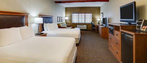 A hotel room with two beds, a desk, a television, a coffee maker, and a dresser.