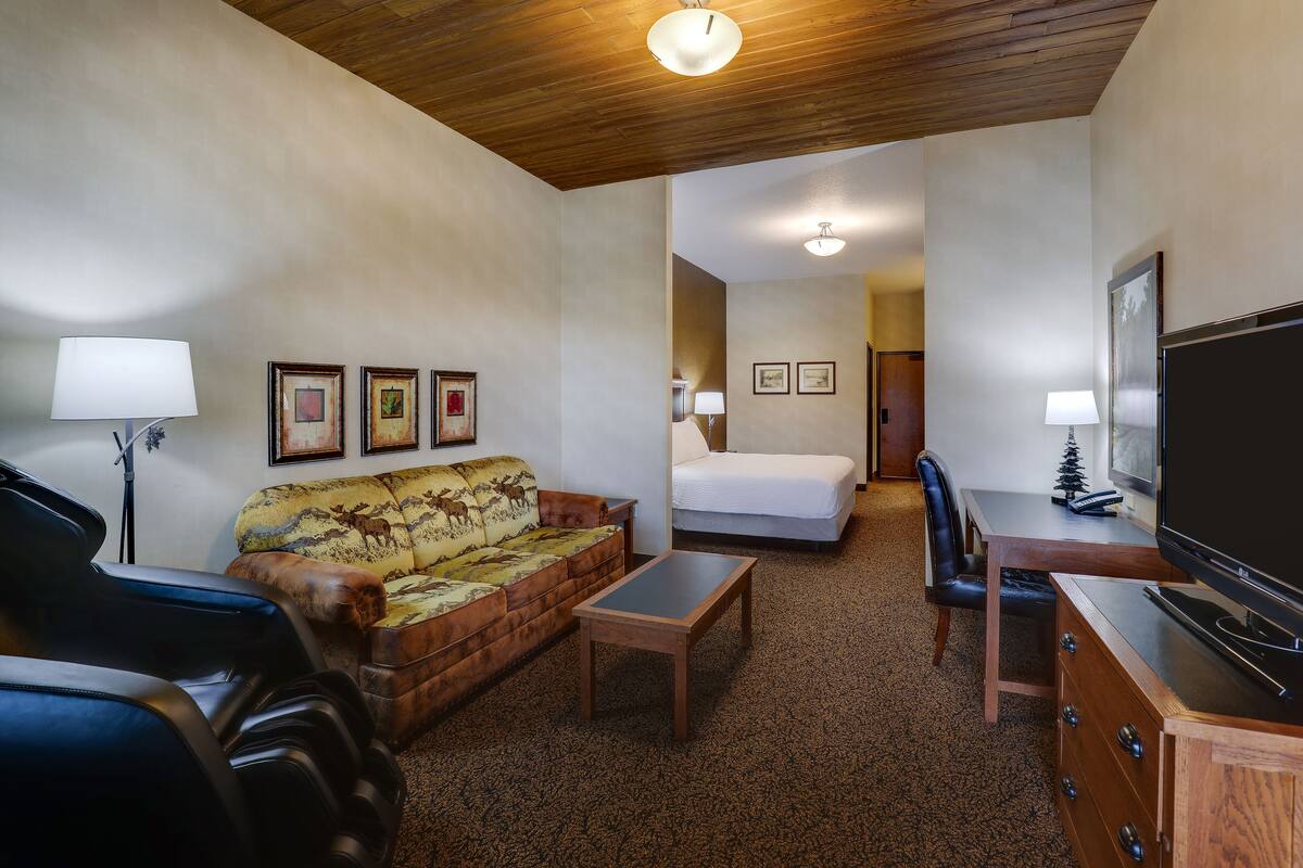 Une chambre d’hôtel équipée d’un canapé, d’un lit, d’un bureau, d’une télévision et de tableaux encadrés aux murs.