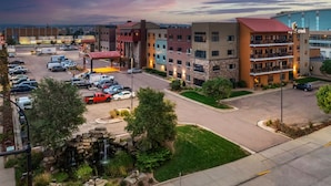 A parking lot with multiple cars, a building with a red roof, and a small waterfall feature. - Stoney Creek Hotel Sioux City (Sioux City)