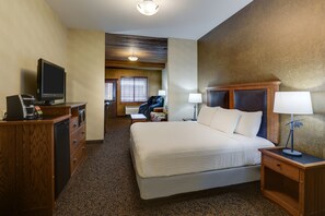 Una habitación de hotel con una cama, un escritorio con televisor, una silla y una lámpara.