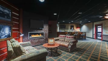 A cozy lounge area with a fireplace, patterned sofas, and a small round table.