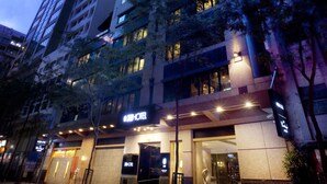 Un hotel moderno con varios pisos, ventanas amplias y una entrada bien iluminada.