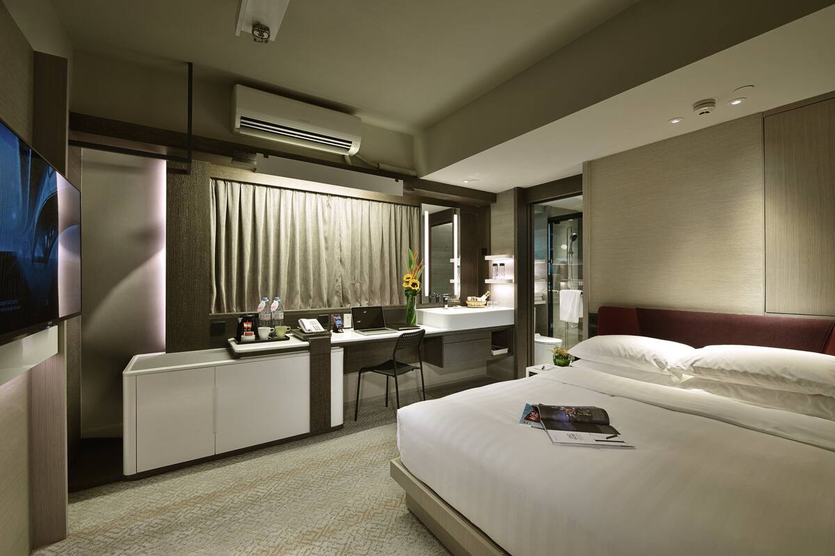 Une chambre d’hôtel moderne équipée d’un lit, d’un bureau, d’une chaise, d’une télévision et d’une salle de bain.