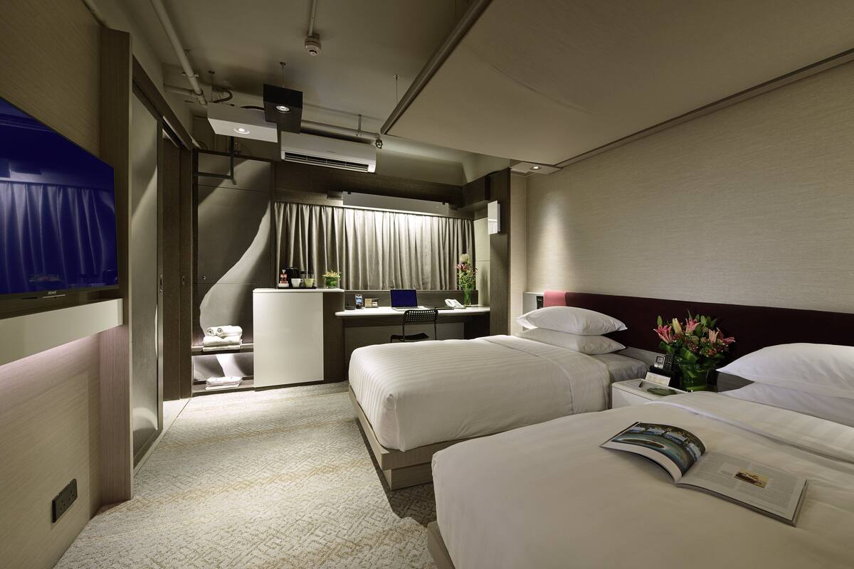 Une chambre d’hôtel avec deux lits, un bureau, une chaise, une coiffeuse et une salle de bain.