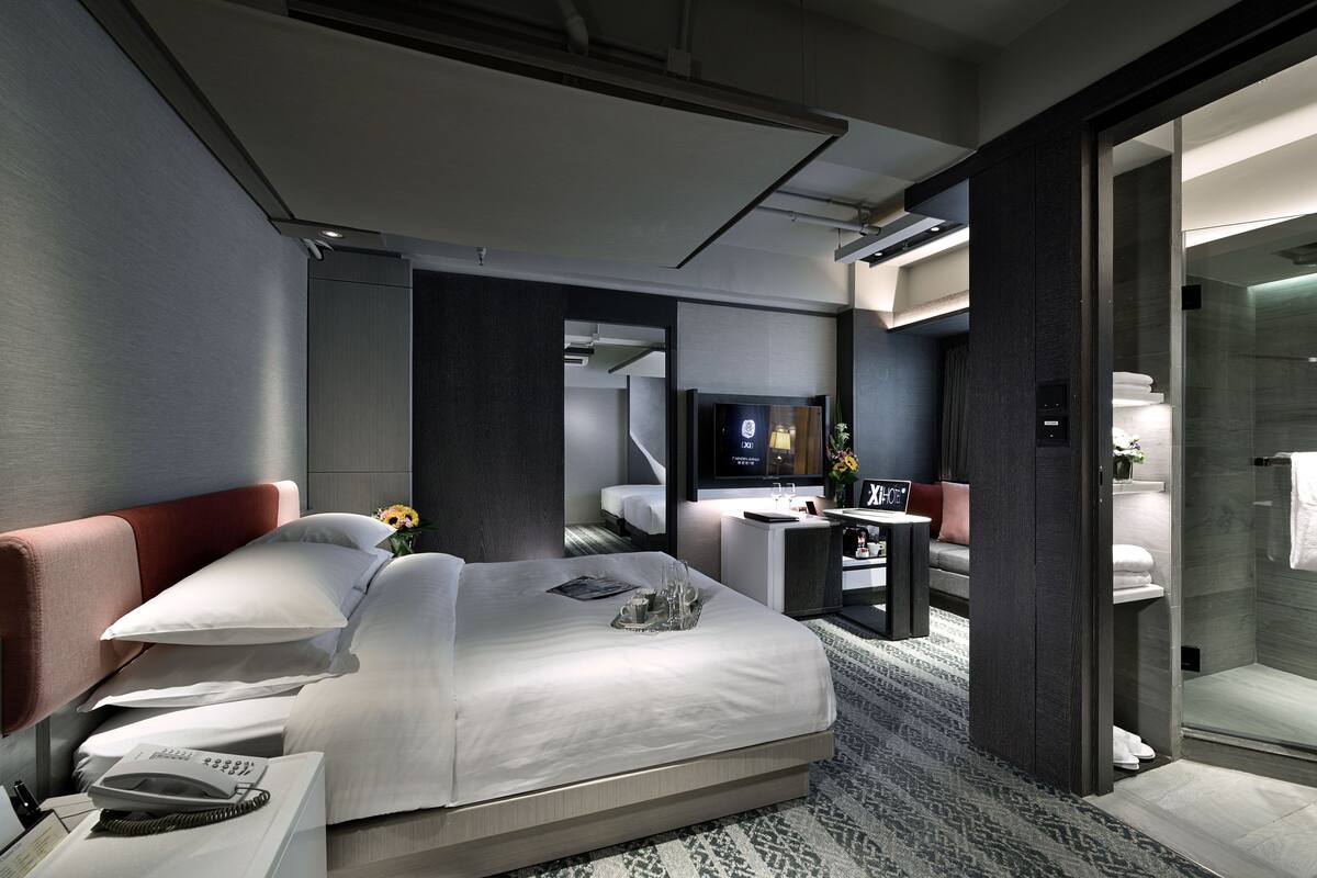 Une chambre d’hôtel moderne équipée d’un grand lit, d’un bureau, d’une télévision et d’un espace douche.