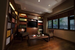 Una biblioteca con estanterías, televisor y una mesa de centro.