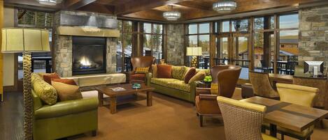 A spacious living area with a stone fireplace, leather sofas, and a view of the outdoors.