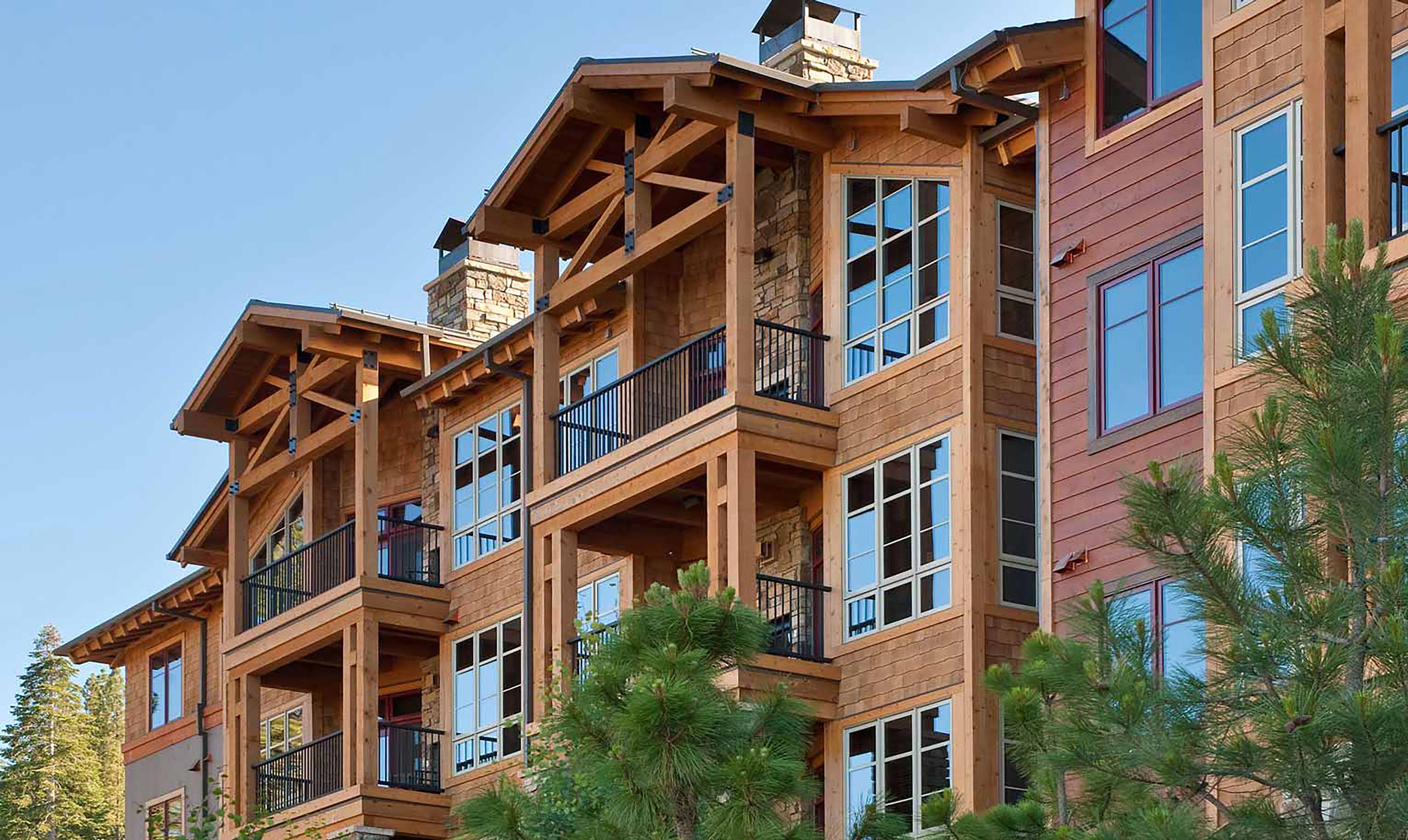 A multi-story building with balconies and large windows, featuring a wooden exterior and stone accents.
