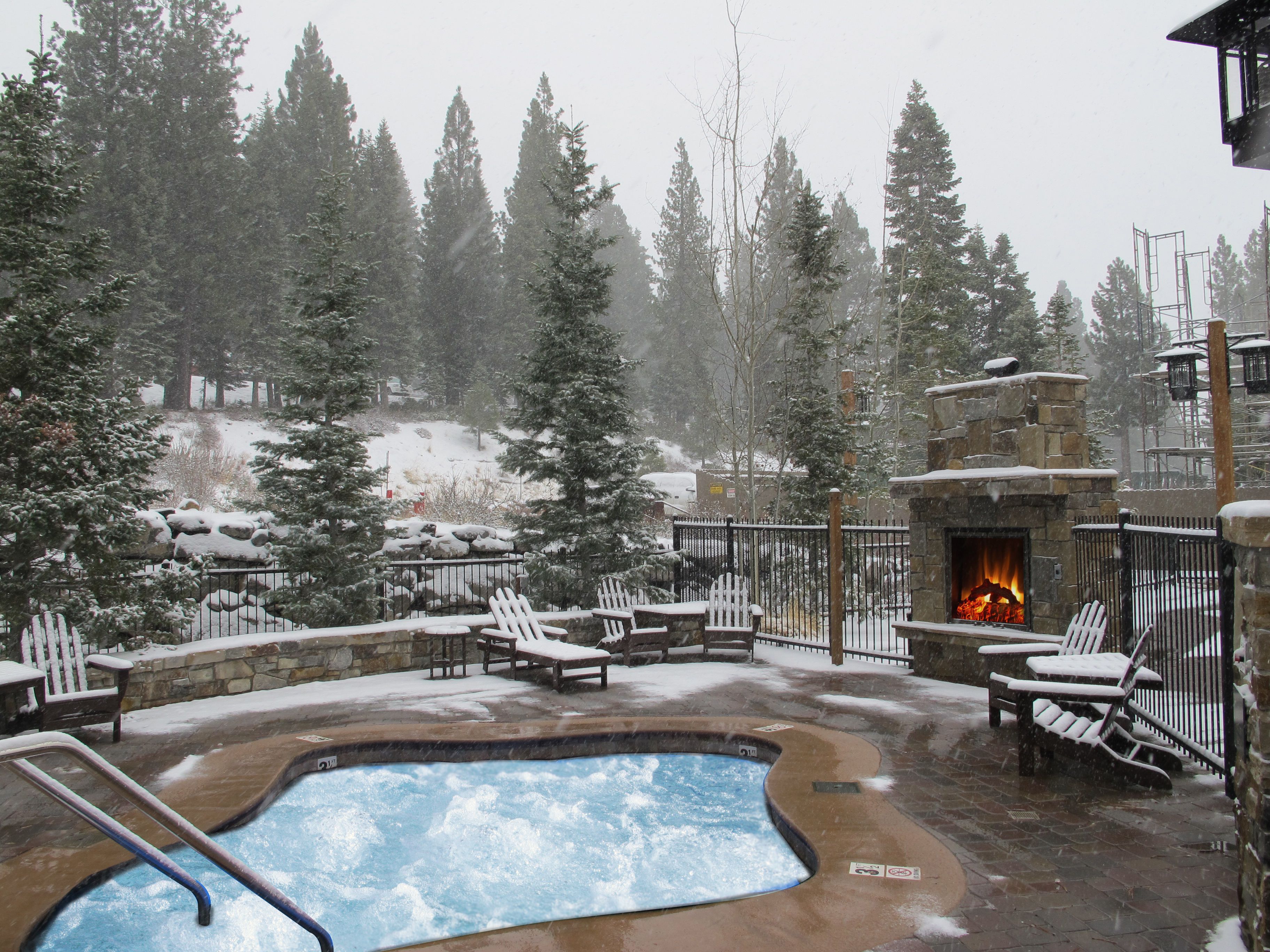 A pool area with lounge chairs and a stone fireplace.