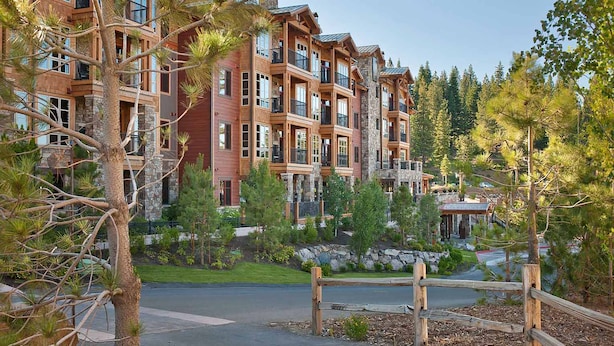 A multi-story hotel with a stone facade, balconies, and a landscaped area with trees and a wooden fence. - Hyatt Vacation Club at Northstar Lodge, Lake Tahoe (Truckee)