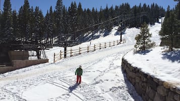 A snowy ski slope with a wooden fence and a stone wall.