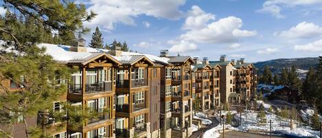 A multi-story hotel with balconies, a swimming pool, and snow on the ground.