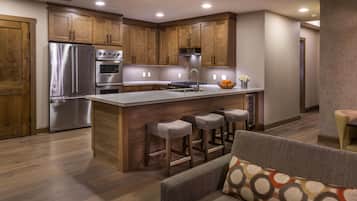 Une cuisine moderne avec des meubles en bois, des appareils électroménagers en acier inoxydable et un îlot central doté de tabourets de bar.