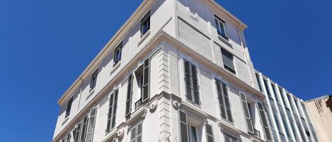 A multi-story building with a classical architectural style, featuring symmetrical windows and decorative moldings.