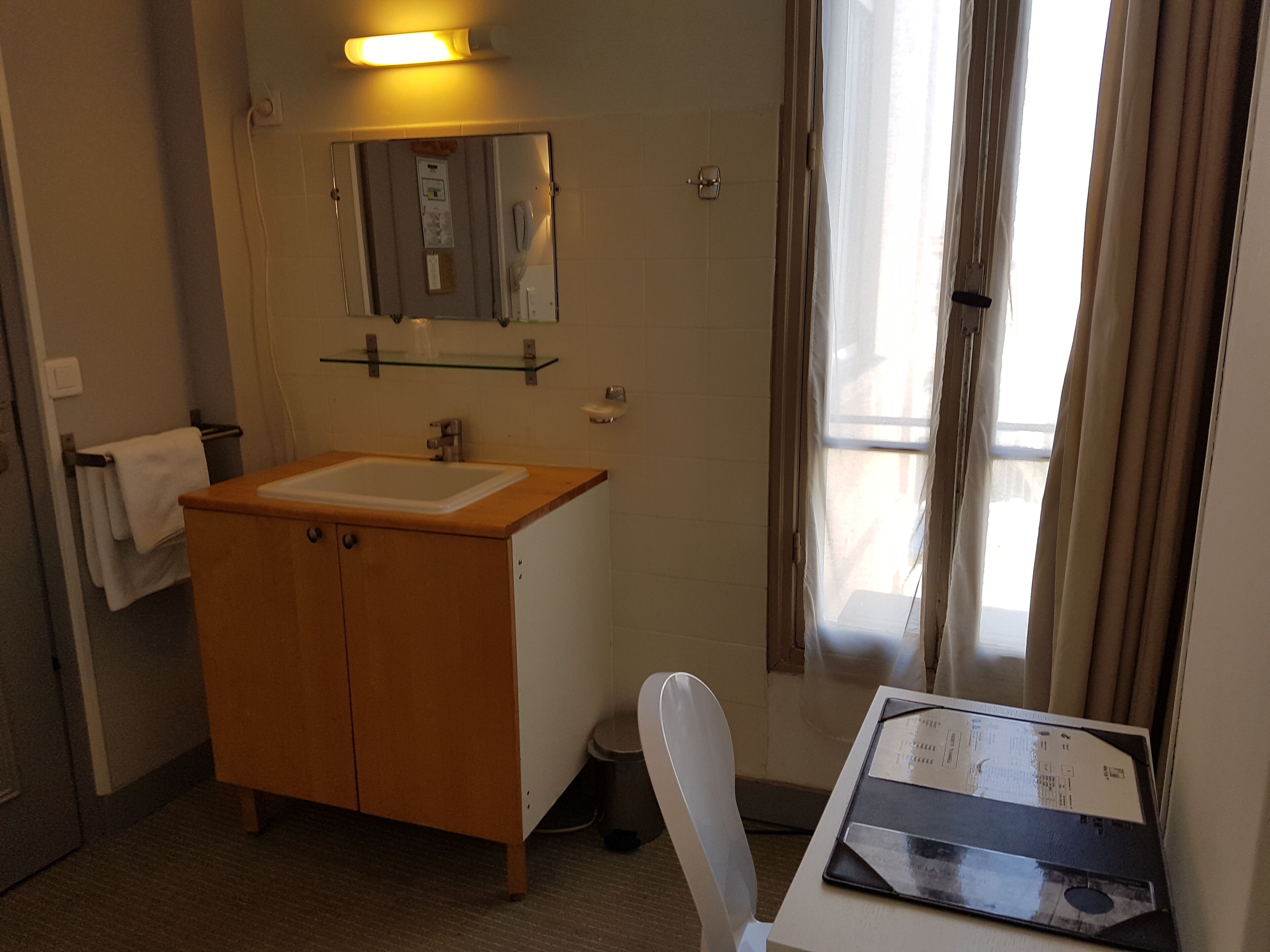A bathroom with a wooden vanity, a mirror, a sink, and a shower area.