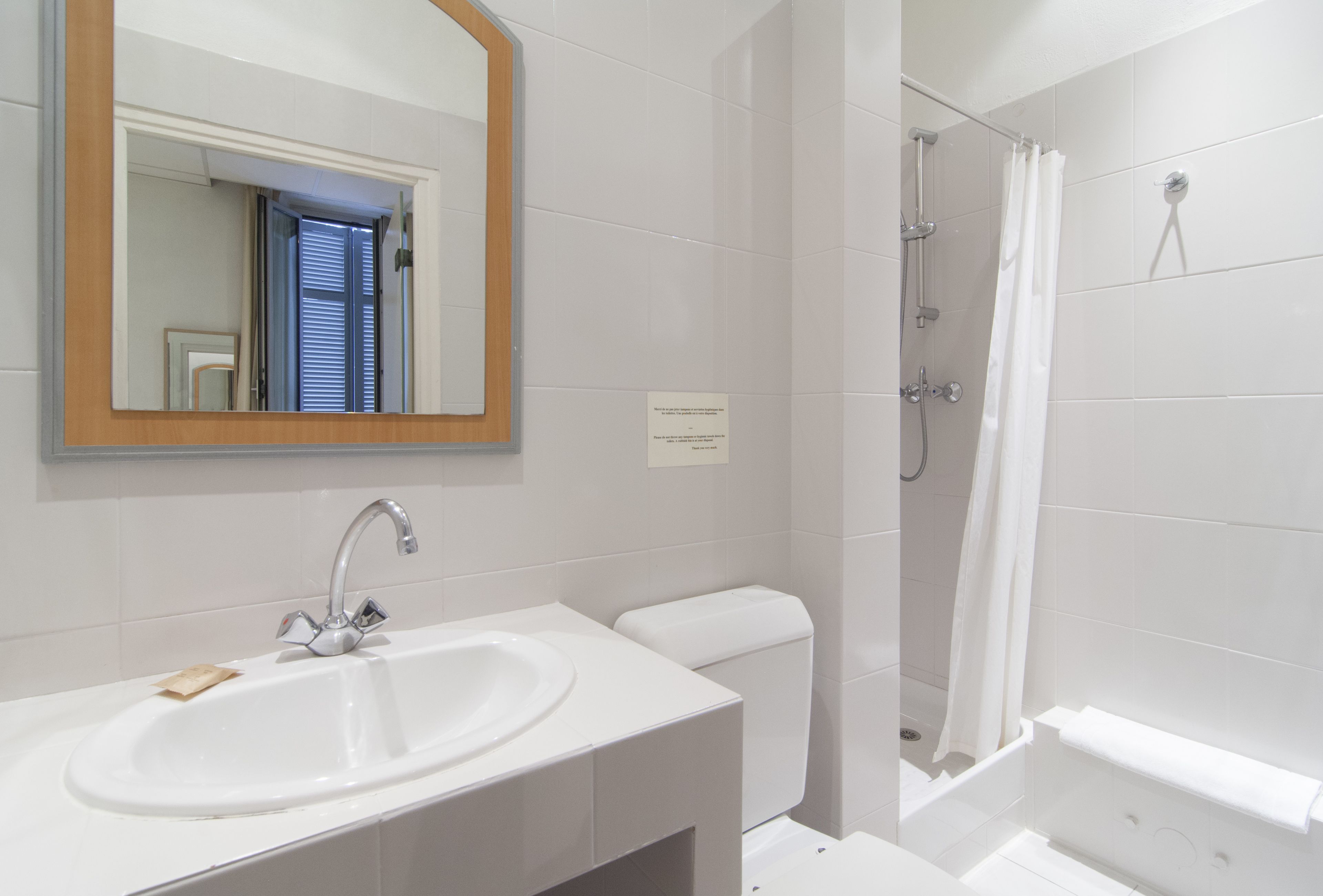 A bathroom with a white sink, mirror, and toilet.