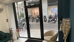 Un hall d'accueil d'hôtel offrant une vue dégagée sur les motos garées à l'extérieur, un comptoir d'accueil et un paillasson sur lequel est inscrit « HÔTEL PLM ».