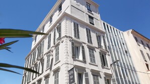 Un immeuble à étages doté d’un style architectural classique, caractérisé par de nombreuses fenêtres et une entrée imposante.