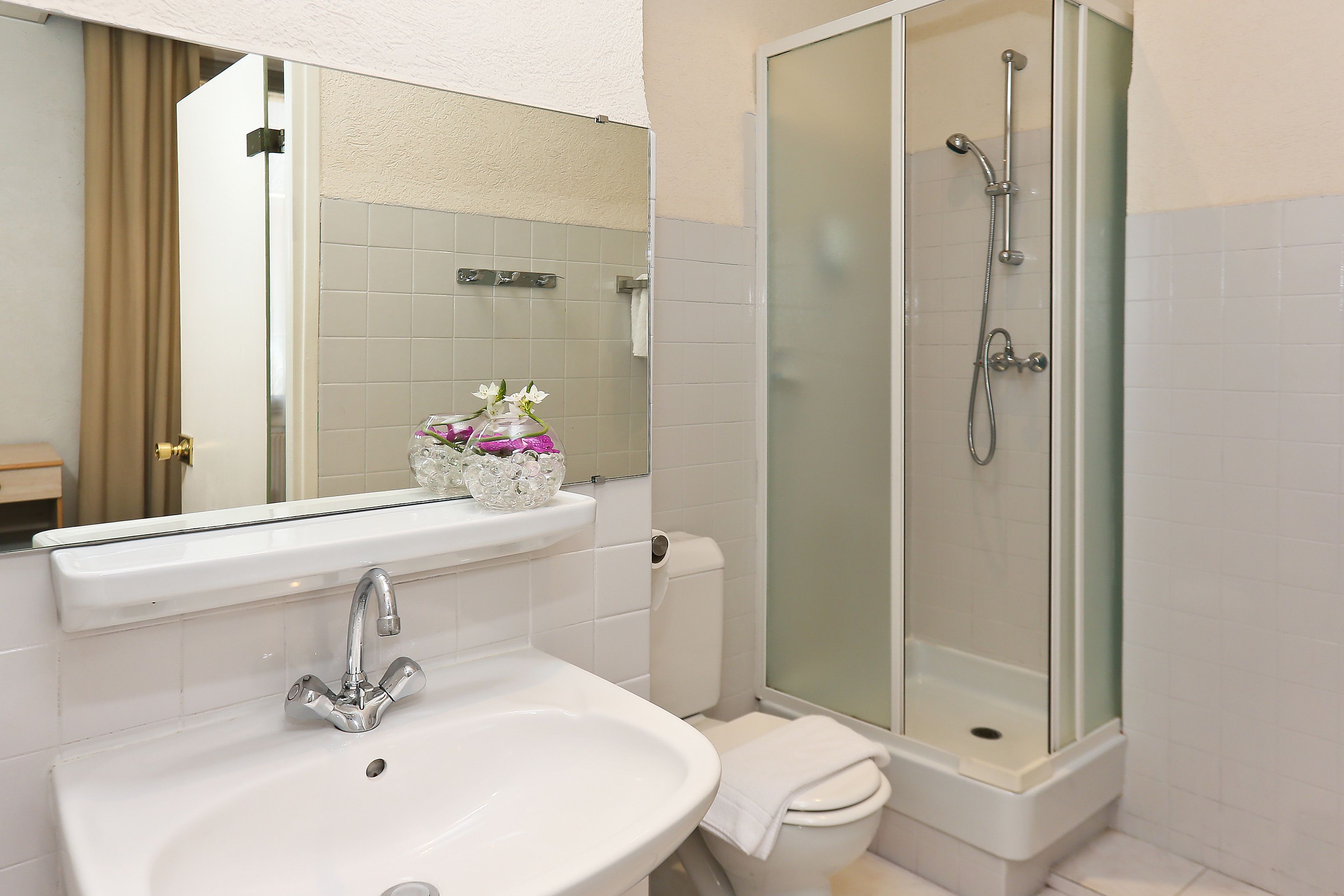 A bathroom with a white sink, a toilet, and a glass-enclosed shower.