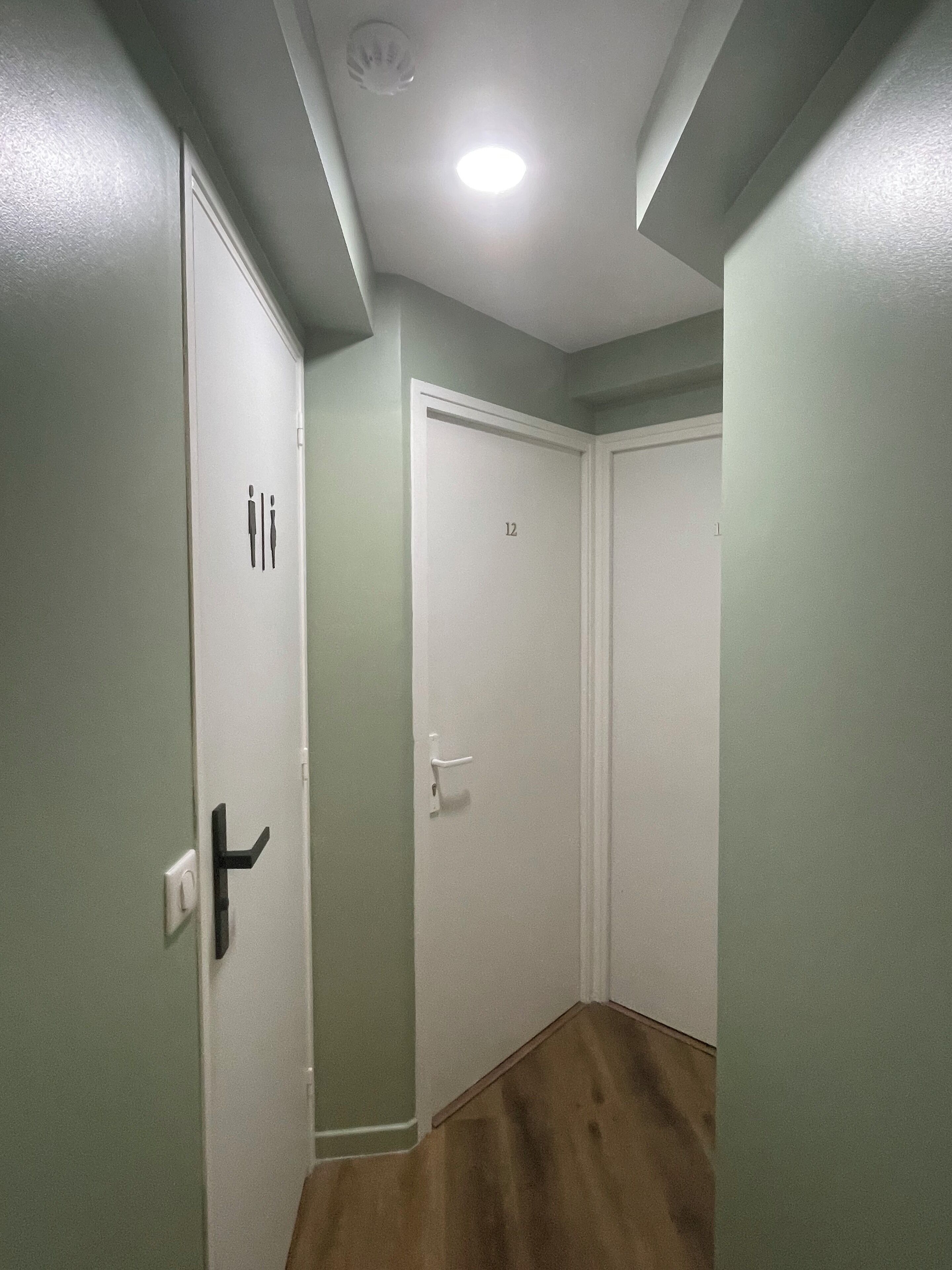 A hallway with two white doors, one marked with the number 12, and a light fixture on the ceiling.