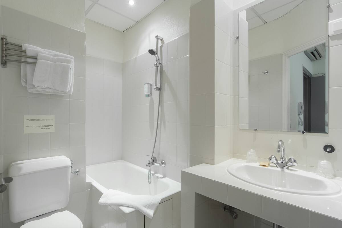 Ein modernes Badezimmer mit Toilette, Badewanne, Dusche, Waschbecken und Spiegel.