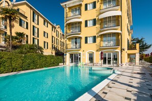 Un hotel con piscina, varios balcones y un jardín bien cuidado.