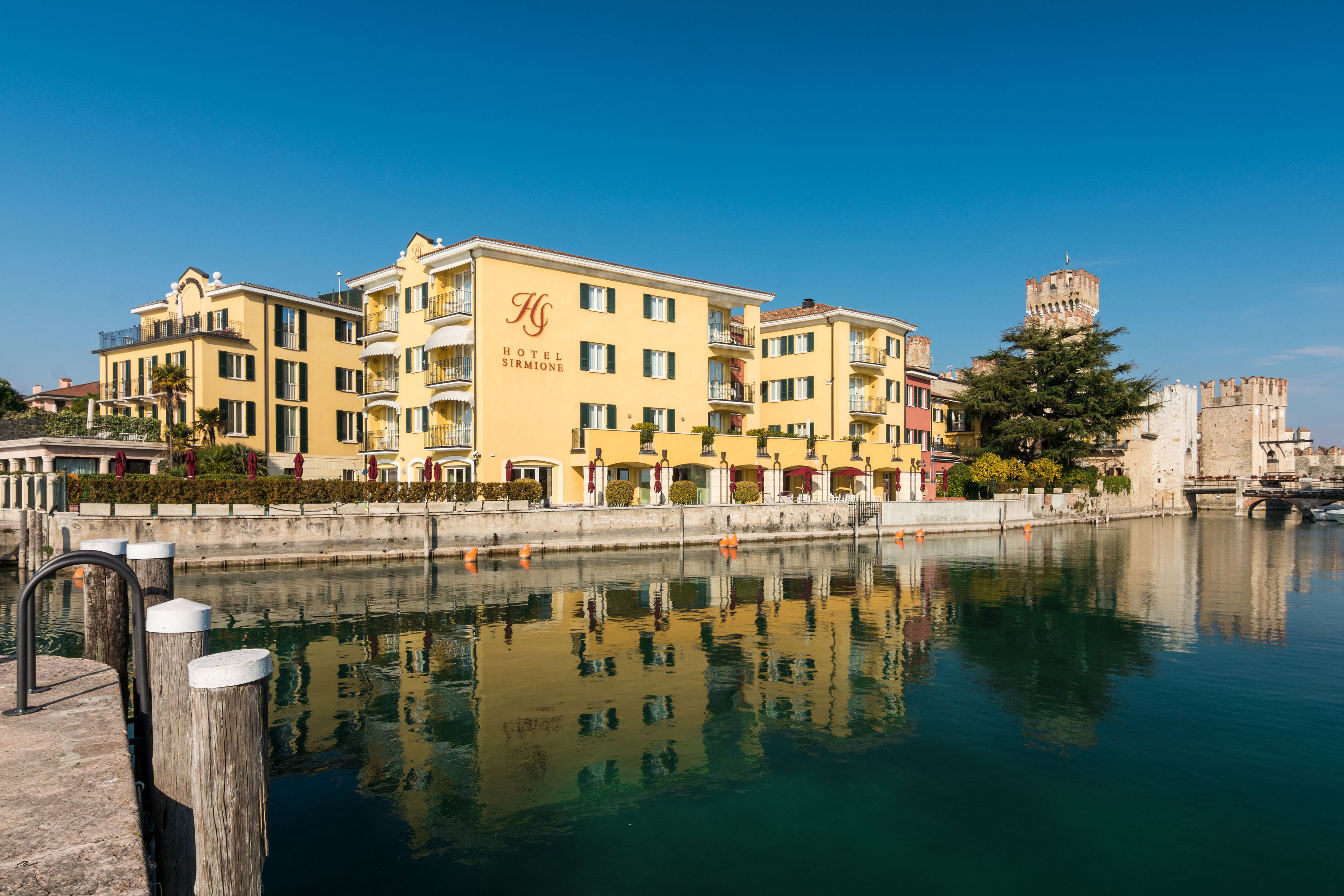 Un hotel de varios pisos, con balcones y reflejado en el agua.
