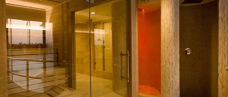 A modern spa area with a glass-enclosed sauna, a separate shower area, and a wooden bench.