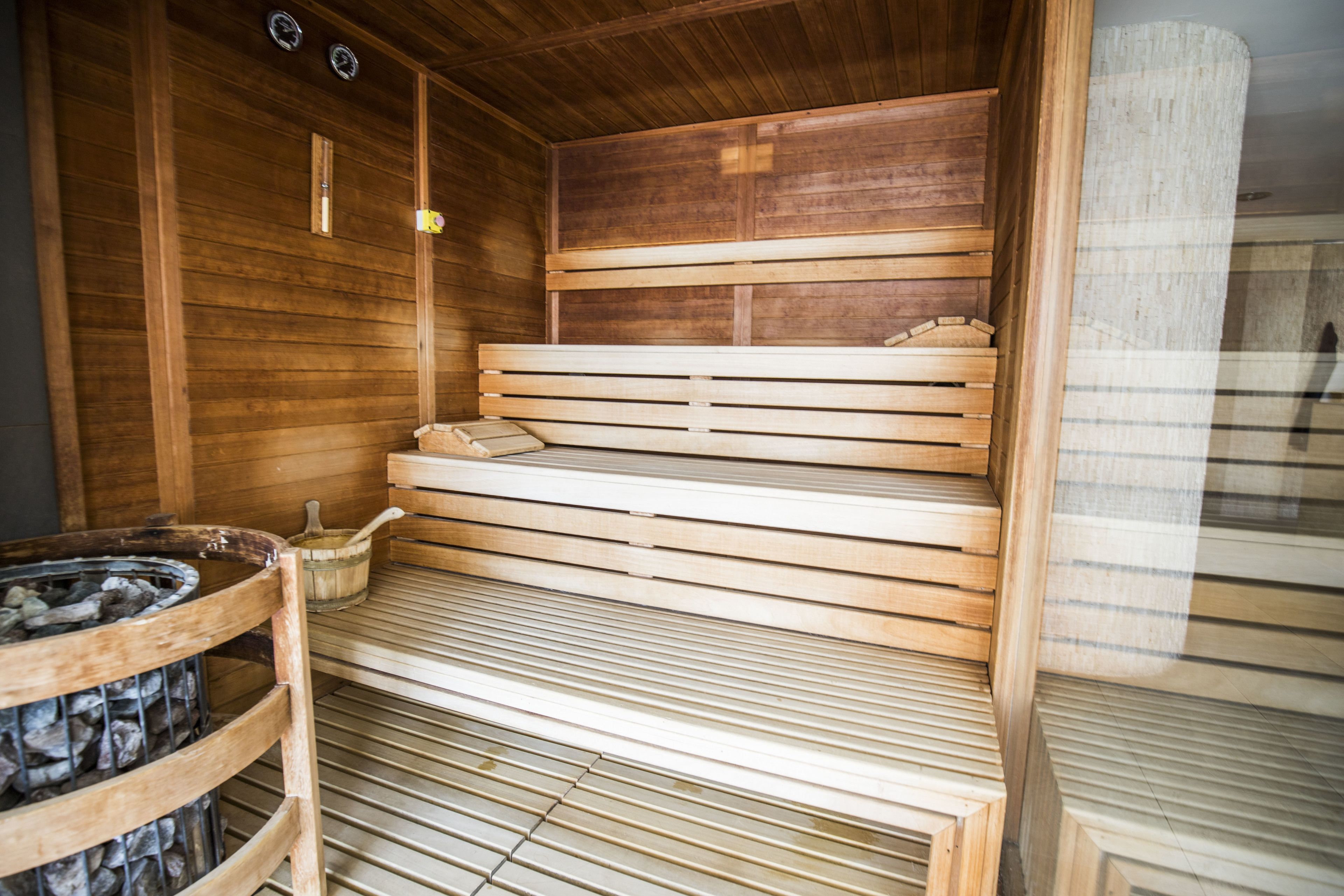 Un sauna avec des bancs en bois et un bassin en pierre.