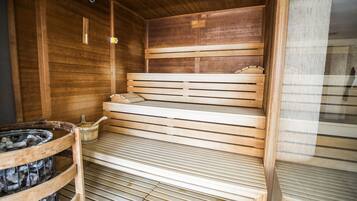 Un sauna avec des bancs en bois et un bassin en pierre.