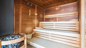 Una sauna de madera con bancos y un calentador de piedra.