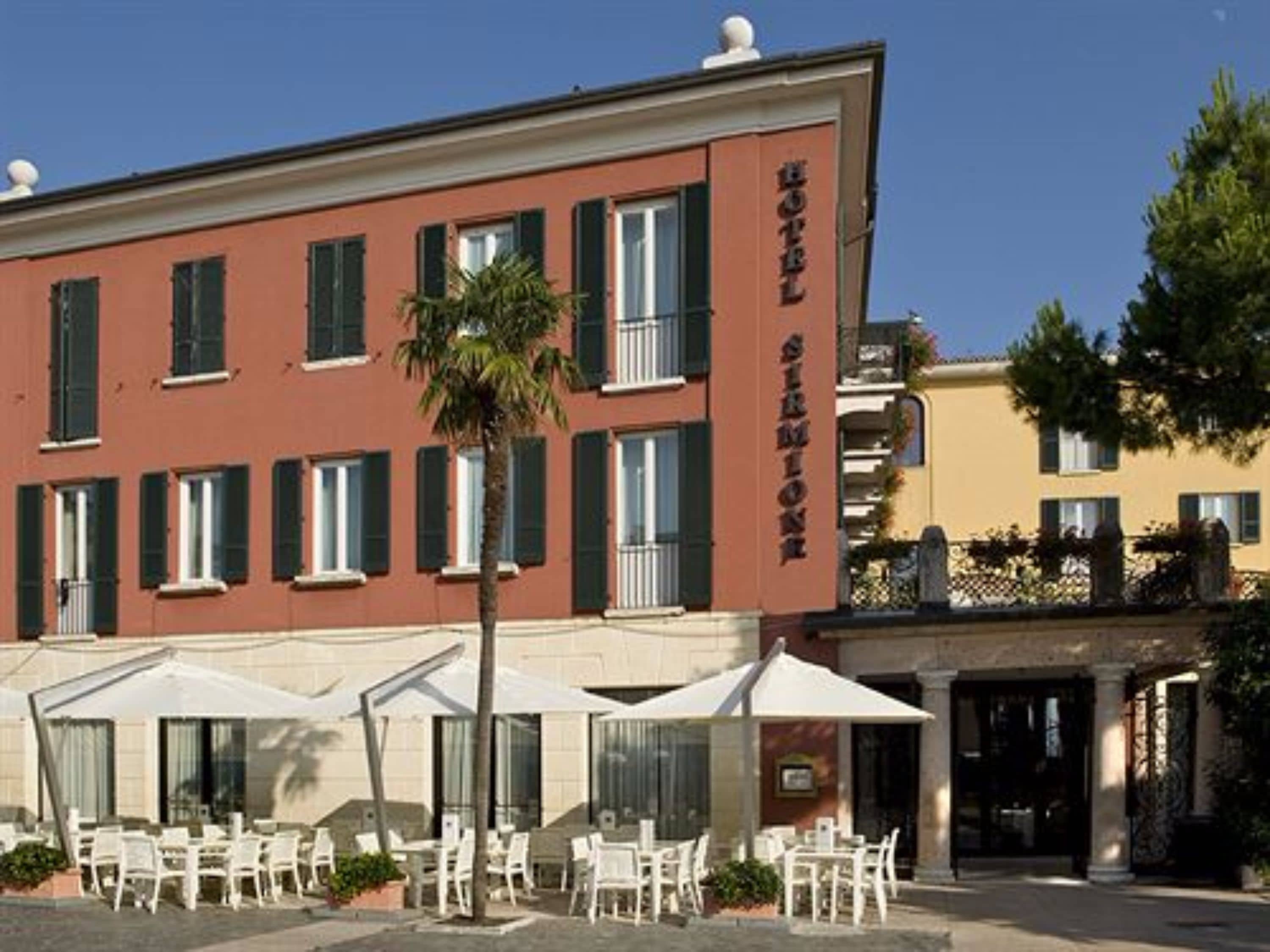 A hotel with outdoor seating and a palm tree.