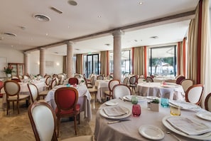 Un comedor amplio con varias mesas y sillas, ventanas grandes y vistas al exterior.