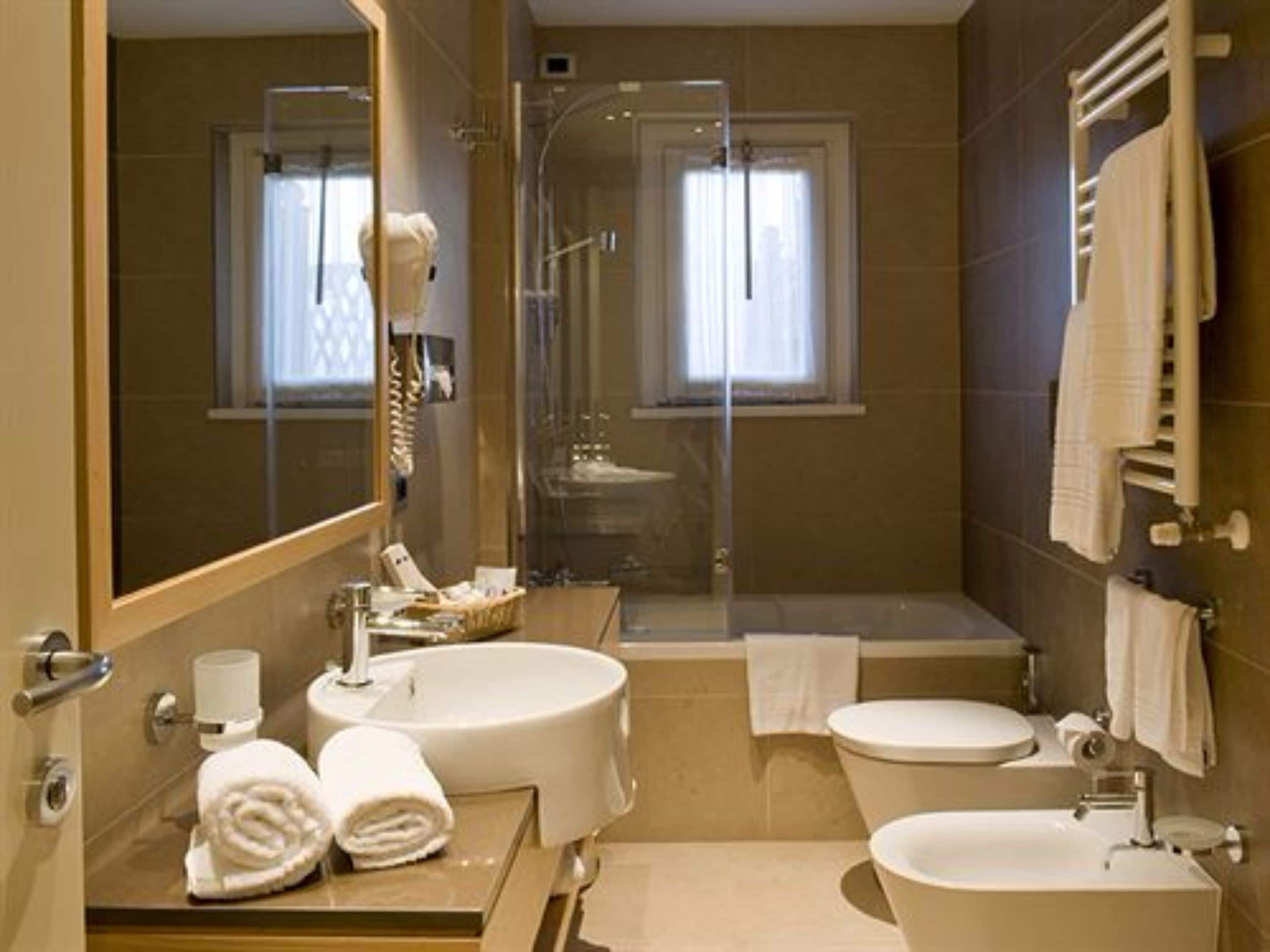 A bathroom with a sink, toilet, and bathtub. There is a towel rack and a mirror.