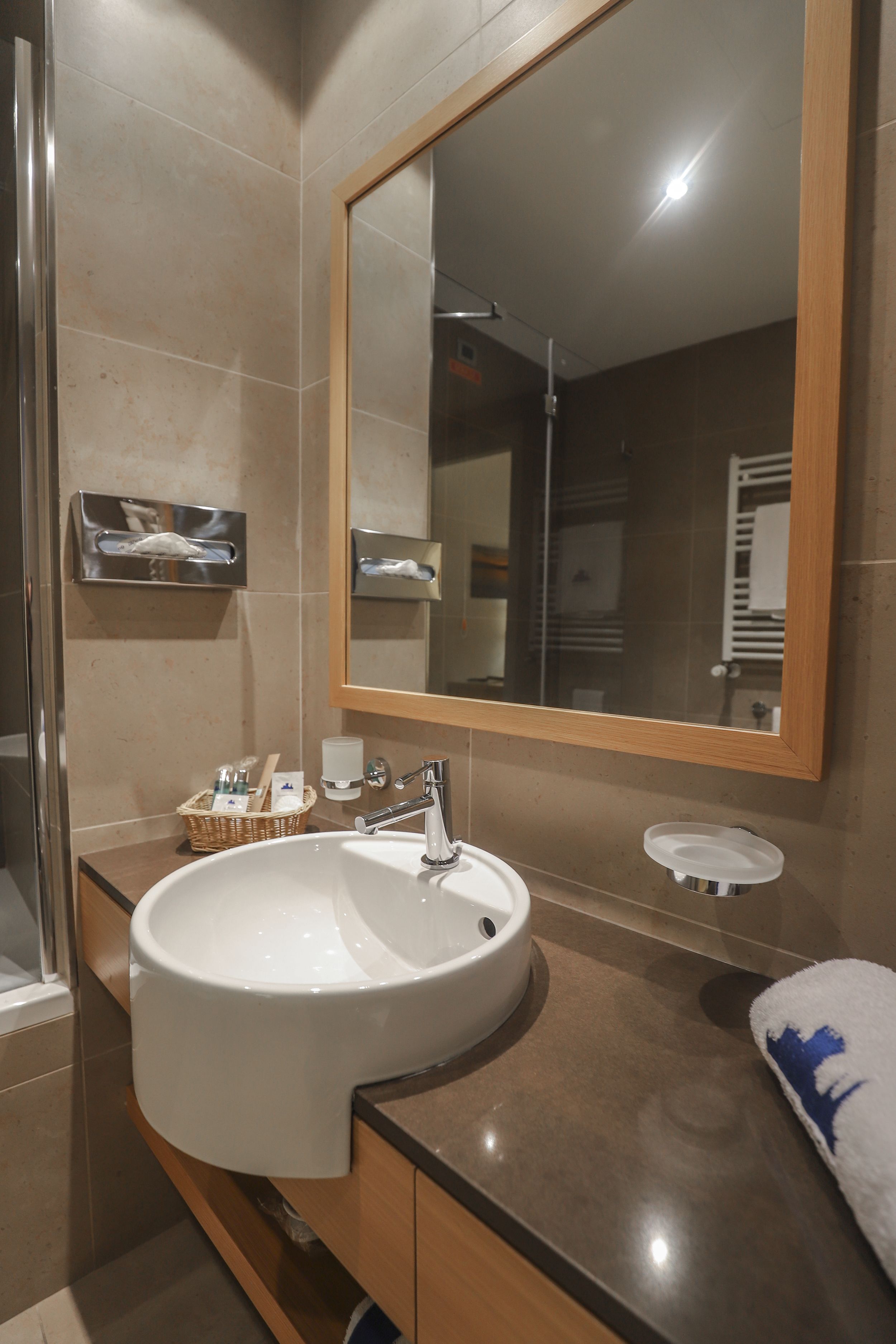 Un baño moderno con un lavamanos grande, un espejo y un perchero para toallas.
